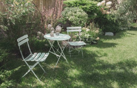 Photo for Beautiful, green, cozy garden corner with a pastel mint table, chairs and white hydrangea flowers. Gardening and landscape design - french style, romantic relaxation nook. - Royalty Free Image