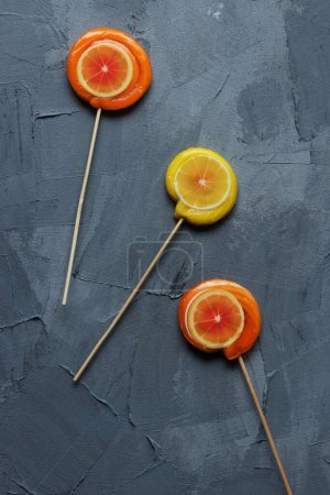 Photo for Orange and lemon lollipops on a grey background - Royalty Free Image