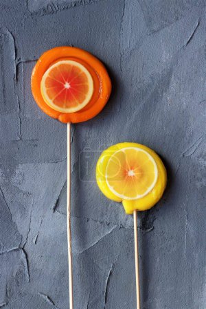Photo for Orange and lemon lollipops on a grey background - Royalty Free Image