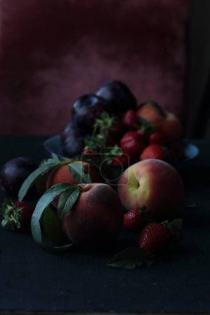 Téléchargez les photos : Pêches, prunes et fraises sur fond noir - en image libre de droit