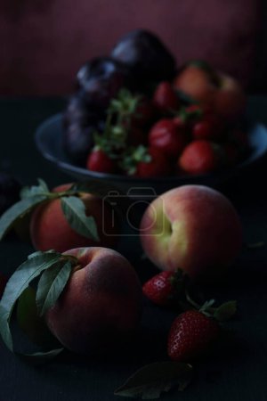 Foto de Melocotones, ciruelas y fresas sobre fondo negro - Imagen libre de derechos