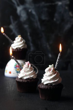 Téléchargez les photos : Cupcakes aux bougies sur fond noir - en image libre de droit