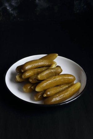 Foto de Cucumber pickle in a plate on a black background - Imagen libre de derechos