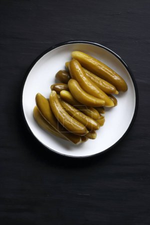 Foto de Cucumber pickle in a plate on a black background - Imagen libre de derechos