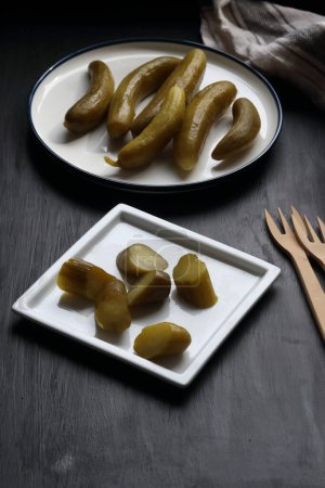 Photo for Cucumber pickle in a plate on a black background - Royalty Free Image