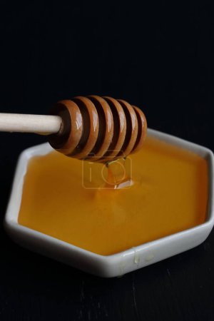 Photo for Fresh Honey with wooden honey spoon on a black background - Royalty Free Image