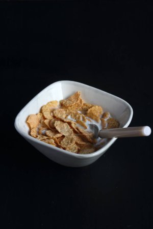 Photo for Bowl of cereal, cornflakes with milk in a bowl on a black background - Royalty Free Image