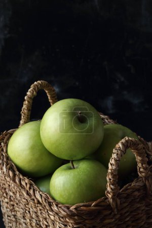Foto de Manzanas verdes en una canasta sobre un fondo negro - Imagen libre de derechos