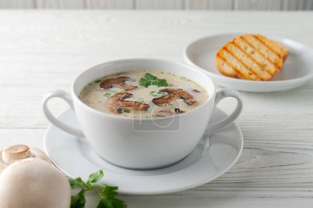 Fresh fragrant mushroom cream soup on a white wooden board. side view