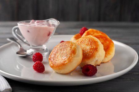 Téléchargez les photos : Gâteaux au fromage maison servis avec yaourt et framboises, vue latérale. - en image libre de droit