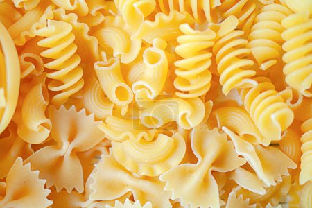 A variety of types and forms of dry Italian pasta. Abstract background