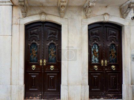 Two vintage double doors decorated with classy art deco ornate outside on the street of Elvas, Portugal.
