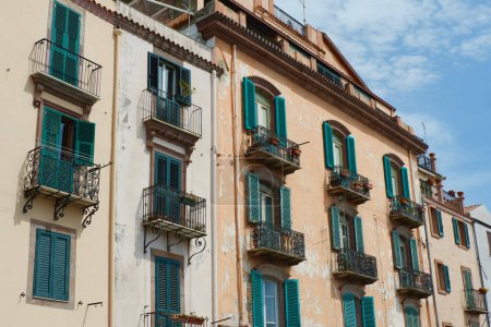 Facade of a vintage buildings downtown Bosa, Sardinia, Italy. Shutters on the windows, Italian aesthetics.
