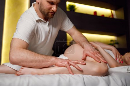 Téléchargez les photos : Man massages woman's legs in spa - en image libre de droit