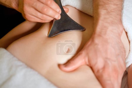 Photo for Strong hands of a male masseur massage the female abdomen using a special tool - Royalty Free Image