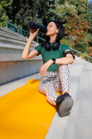 Foto de Momento refrescante: Atleta joven que bebe agua al aire libre - Imagen libre de derechos