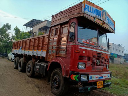 Foto de Kolhapur, India- 01 de noviembre 2022; Vista lateral de camión de color rojo estacionado junto a la carretera, edificios residenciales, árboles verdes en el fondo. Imagen capturada temprano en la mañana. enfoque selectivo. - Imagen libre de derechos