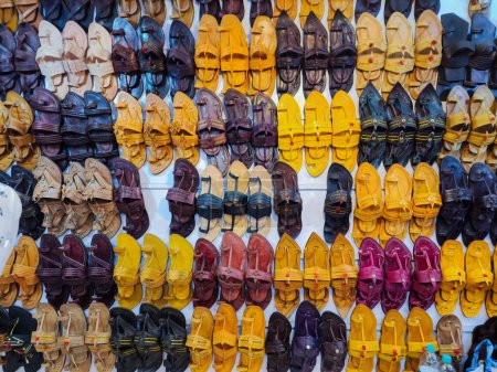 Photo for Stock photo of popular and traditional kolhapuri chappal display on wall for sale in the local shop.It is handmade leather chappal with unique design and color at Kolhapur, Maharashtra, India. - Royalty Free Image