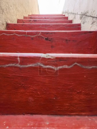 Téléchargez les photos : Stock photo of old concrete staircase painted with maroon color, light yellow color painted wall beside the staircase,Picture captured under natural light at Gulbarga, Karnataka, India.selective focus - en image libre de droit