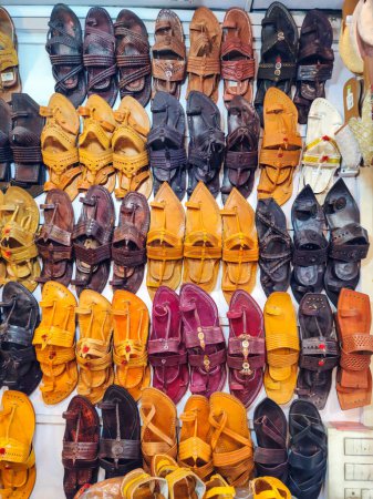 Photo for Stock photo of popular and traditional kolhapuri chappal display on wall for sale in the local shop.It is handmade leather chappal with unique design and color at Kolhapur, Maharashtra, India. - Royalty Free Image