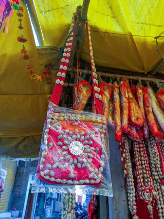 Photo for Stock photo of beautiful and traditional handmade red color bag decorated with white color cowry shell,hanging outside of the shop, Picture captured under natural light at Tuljapur, Maharashtra, India - Royalty Free Image