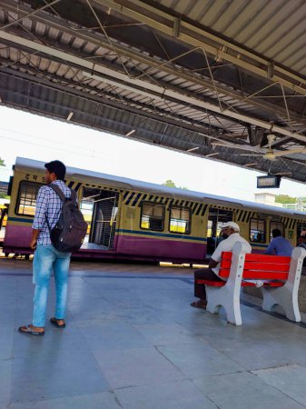 Foto de Hyderabad, India- 12 de octubre de 2022; En la bulliciosa plataforma ferroviaria de la India, varias personas están sentadas en un banco, mientras que otros están de pie, llevando sus maletas, y esperan pacientemente su tren. - Imagen libre de derechos