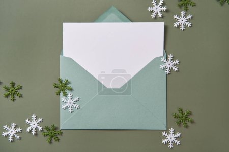 Téléchargez les photos : Carte de Noël à plat. Carte vide dans une enveloppe verte. Modèle de vacances et d'invitation. - en image libre de droit