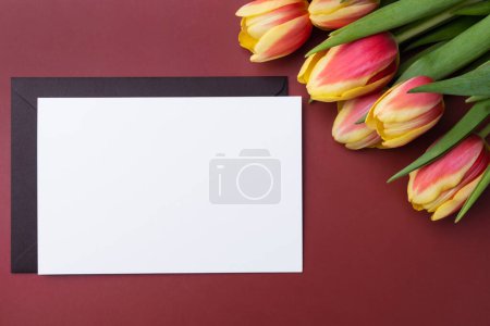 Photo for Greeting card mockup or thank you card template with bouquet of tulips on a burgundy background. - Royalty Free Image