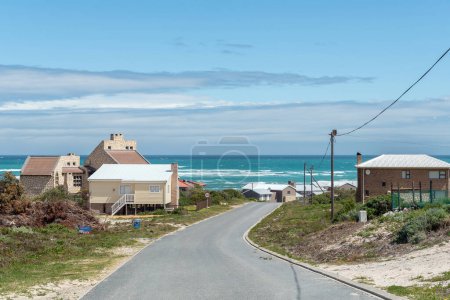 Téléchargez les photos : Suiderstrand, Afrique du Sud - 22 sept. 2022 : Une scène de rue, avec des maisons, à Suiderstrand, un hameau dans le parc national des Agulhas près du point le plus au sud de l'Afrique, Cap L'Agulhas. - en image libre de droit