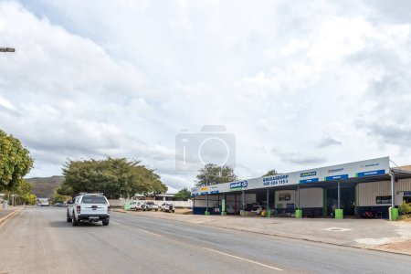 Photo for Bredasdorp, South Africa - Sep 23, 2022: A street scene, with a battery, brake and tyre workshop, in Bredasdorp in the Western Cape Province. Vehicles are visible - Royalty Free Image