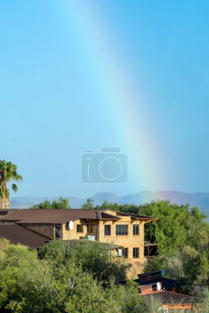Photo for Augrabies National Park, South Africa - Feb 27, 2023: A rainbow, caused by the spray of the Augrabies Falls is visible above the restaurant and offices of the park - Royalty Free Image