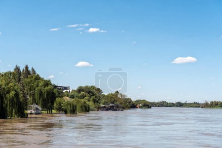Photo for Upington, South Africa - Feb 24, 2023: A sightseeing boat and a floating restaurant deck on the banks of a flooded Orange River at Upington - Royalty Free Image
