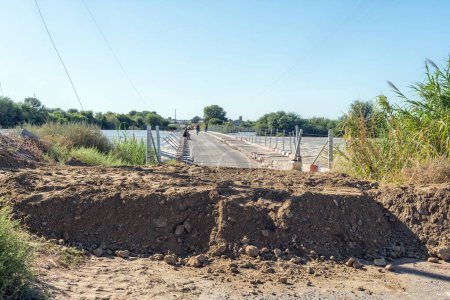 Photo for Kanoneiland, South Africa - Feb 25, 2023: The Eendrag bridge over the flooded Orange River at Kanoneiland near Upington. A gravel wall protects crops against flooding - Royalty Free Image