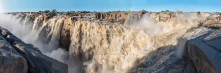 Photo for Sunset at flooded viewpoint at the Augrabies waterfalls in the Orange River. A rainbow is visible - Royalty Free Image