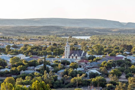 Téléchargez les photos : Prieska, Afrique du Sud - 28 février 2023 : Prieska vu de la réserve naturelle de Koppie. L'église réformée néerlandaise et la rivière Orange inondée sont visibles - en image libre de droit