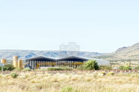 Téléchargez les photos : Prieska, Afrique du Sud - 1er mars 2023 : Cour préfabriquée d'une tour à vent à Prieska, dans la province du Cap Nord. Une voie ferrée est visible - en image libre de droit
