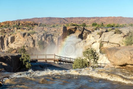 Photo for A rainbow is visible over a boardwalk at the Augrabies waterfalls in the Orange River. The river is in flood - Royalty Free Image