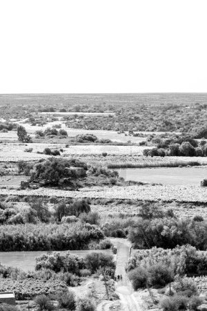 Photo for People crossing a flooded bridge over a channel of the flooded Orange River as seen from Tierberg at Keimoes in the Northern Cape. Monochrome - Royalty Free Image