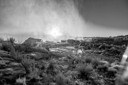 Photo for Sunrise through the spray of a flooded Augrabies Falls. Boardwalks are visible. Monochrome - Royalty Free Image
