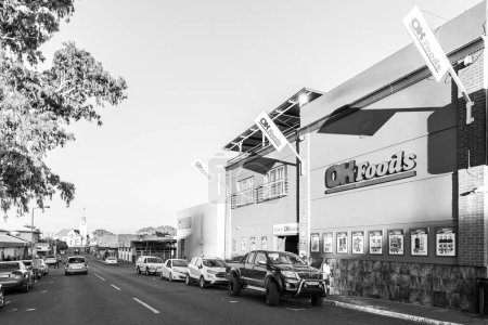 Foto de Prieska, Sudáfrica - 28 feb 2023: Una escena callejera, con un supermercado, gente, vehículos y una iglesia, en Prieska, en la Provincia del Cabo Norte. Monocromo - Imagen libre de derechos