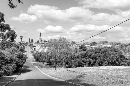 Foto de Stanford, Sudáfrica - 20 de septiembre de 2022: Una escena callejera en Stanford, en la Provincia Occidental del Cabo. La iglesia reformada holandesa es visible. Monocromo - Imagen libre de derechos