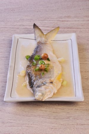Téléchargez les photos : Poisson threadfin à quatre doigts cuit à la vapeur avec cordia dichotoma sur plaque blanche. - en image libre de droit