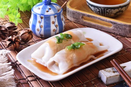 Steamed rice rolls with fresh prawn filling served in a dish  on wooden table 