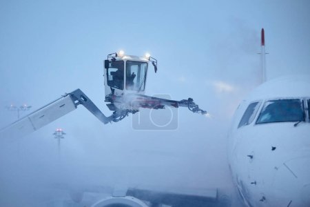 Photo for Deicing of airplane before flight. Winter day at airport during snowfall - Royalty Free Image