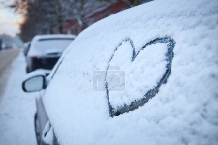 Photo for Heart shape as love sign on snowy car window. Parking on snow covered city street in winter. - Royalty Free Image