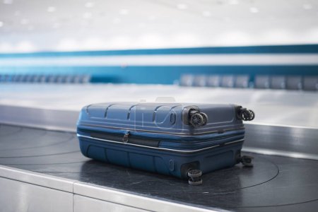 Téléchargez les photos : Traveling by airplane. Blue suitcase on baggage claim in airport terminal. - en image libre de droit