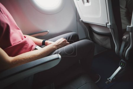 Foto de Hombre descansando durante el vuelo. Espacio para las piernas entre asientos en avión comercial. - Imagen libre de derechos