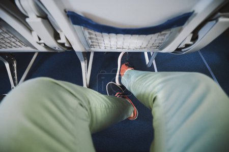 Téléchargez les photos : Personal perspective on legroom between seats in airplane. Man resting during flight. - en image libre de droit