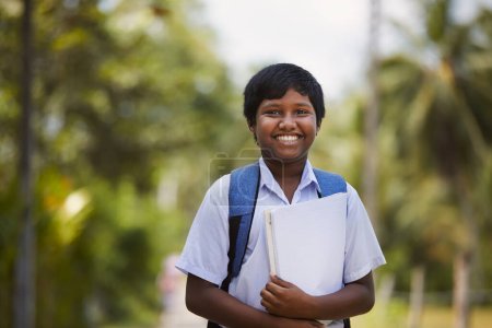 Téléchargez les photos : Un écolier en uniforme va à pied à l'école. Portrait garçon sur la route rurale au Sri Lanka - en image libre de droit