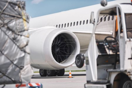 Photo for Preparation airplane at airport. Loading of cargo containers against jet engine of plane before flight - Royalty Free Image